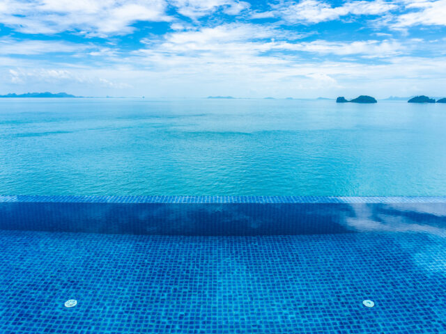 beautiful-outdoor-swimming-pool-with-sea-ocean-white-cloud-blue-sky_Easy-Resize.com